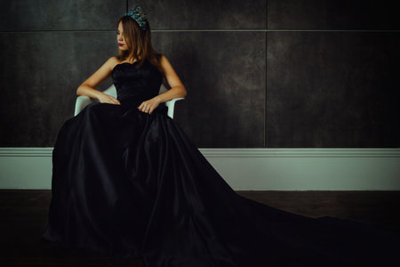 Young beautiful woman in long black dress and diamond crown. Studio shotの写真素材