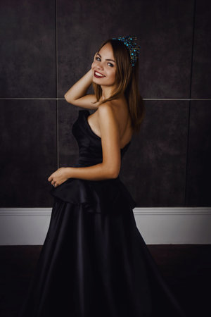 Young beautiful woman in long black dress and diamond crown. Studio shotの写真素材