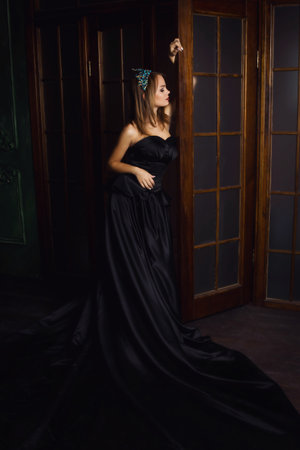 Young beautiful woman in long black dress and diamond crown. Studio shotの写真素材