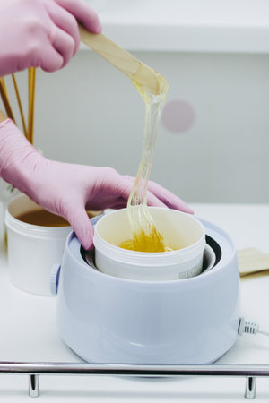 Hands in pink glows making waxing or sugaring epilationの写真素材