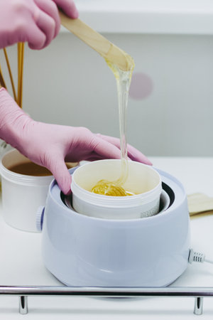 Hands in pink glows making waxing or sugaring epilationの写真素材