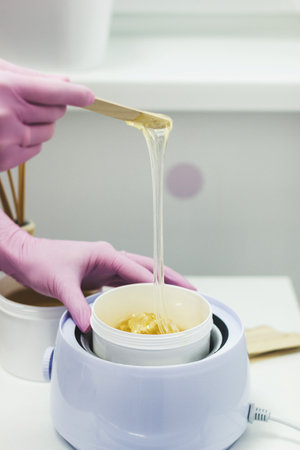 Hands in pink glows making waxing or sugaring epilationの写真素材