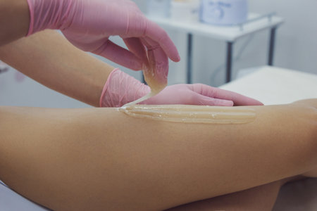 Woman using sugaring paste to shave legsの写真素材