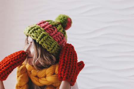 Portrait of a beautiful young woman wearing knitted hat and mittensの写真素材