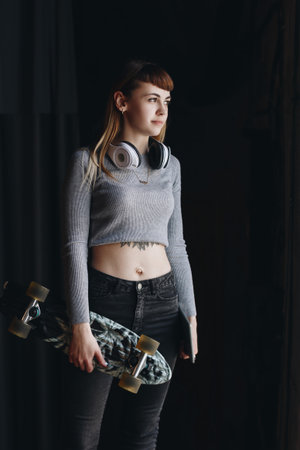 Young girl with skateboard and headphones in loft appartmentの写真素材