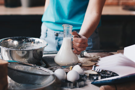 Woman holding bottle with milk while baking a cakeの写真素材