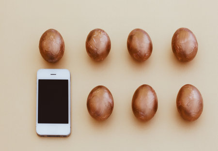 Two rows of golden Easter eggs and smartphoneの写真素材