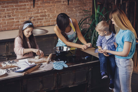 Two young women and two kids - boy and girl - have fun in the kitchenの写真素材