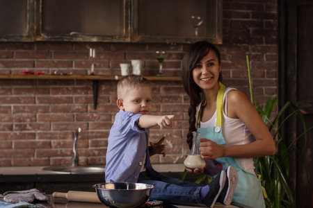 Mom with her 2 years old son cooking holiday pie in the kitchenの写真素材