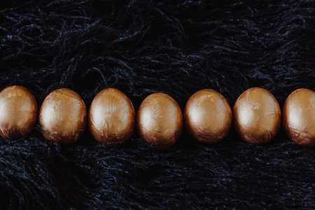 Row of golden Easter eggs on the black fur backgroundの写真素材