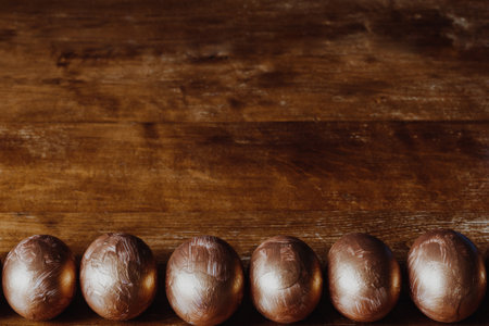 Row of golden Easter eggs on the rustic wooden background. Copy spaceの写真素材