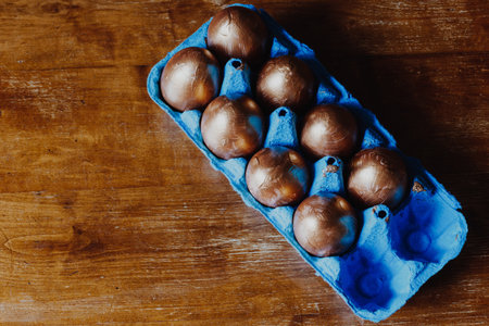 Golden Easter eggs in blue box on the wooden table. Top viewの写真素材