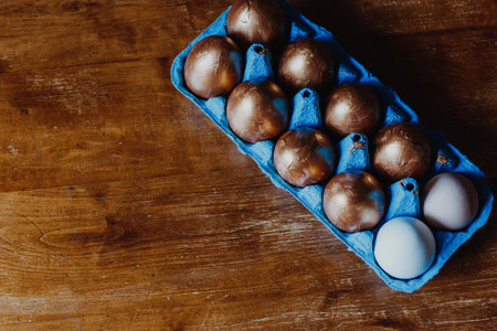 Golden and white Easter eggs in blue box on the wooden table. Top viewの写真素材