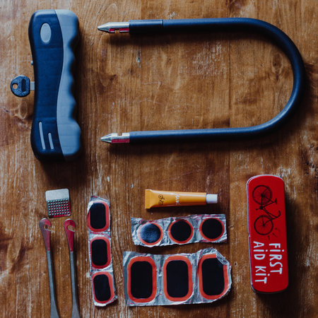 Bicycle U shaped lock and bicycle repair kit on wooden background. Top view