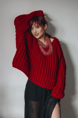 Portrait of young woman in stylish red oversized sweater and black skirtの写真素材