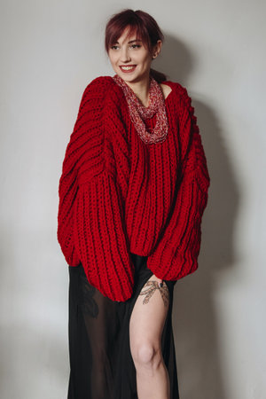 Portrait of young woman in stylish red oversized sweater and black skirtの写真素材