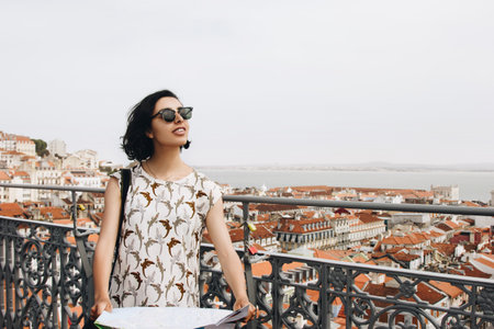 Young woman tourist with glasses looking at the map on the hill of old european cityの写真素材