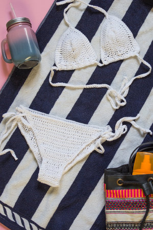 Knitted white swimsuit on stripped towel. Top shotの写真素材