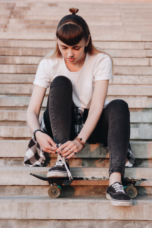 Hipster girl with skate board tying her shoelacesの写真素材