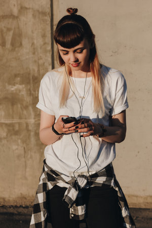 Hipster girl listening to music in the city at sunsetの写真素材