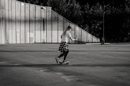 Hipster girl riding skate board in the city. Black and white shotの写真素材
