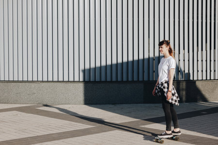 Hipster girl riding skate board in the cityの写真素材