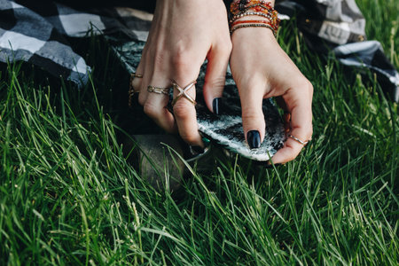 Close-up of woman hands with rings holding skate board on the grass