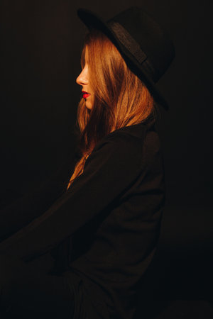 Portrait of a young caucasian woman with hat in dark studioの写真素材