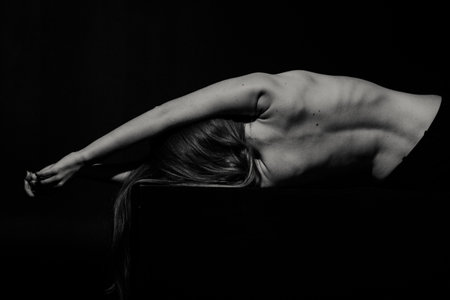 Back of young caucasian woman in dark studioの写真素材