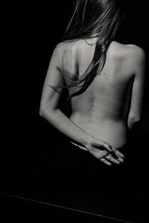 Back of young caucasian woman in dark studioの写真素材