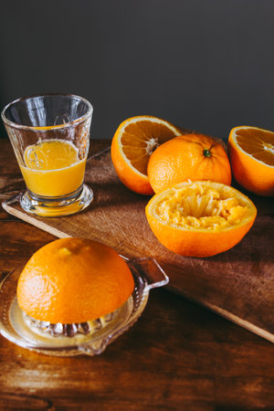 Oranges, juice and squeezer on wooden table