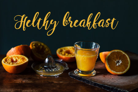 Oranges, juice and squeezer on wooden tableの写真素材