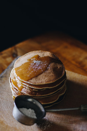 Stack of pancakes with honey and sugar powder on wooden boardの写真素材