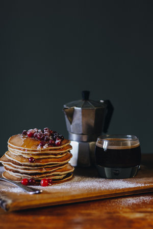 Delicious breakfast with pancakes with maple syrup and cranberries and coffeeの写真素材