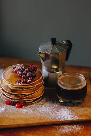 Delicious breakfast with pancakes with maple syrup and cranberries and coffee