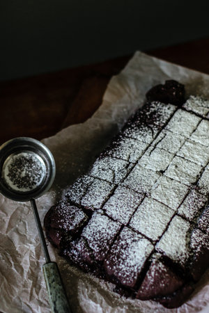 Chocolate brownie served with powdered sugar on a baking paperの写真素材