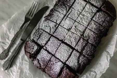 Chocolate brownie served with powdered sugar on a baking paperの写真素材