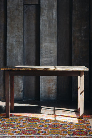 Old wooden table in the dark room with natural sun light and carpetの写真素材
