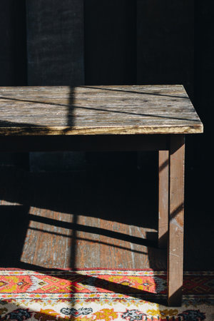 Old wooden table in the dark room with natural sun light and carpetの写真素材