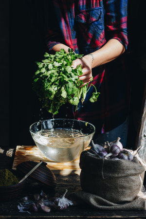 Woman washing fresh greenery in a bowlの写真素材