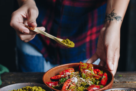 Woman pouring spices into the bowl with red hot chili peppersの写真素材