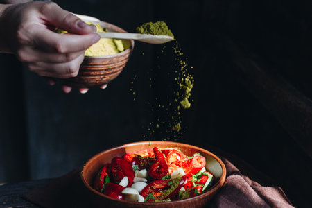 Woman pouring spices into the bowl with red hot chili peppersの写真素材