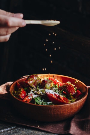 Woman pouring spices into the bowl with red hot chili peppersの写真素材