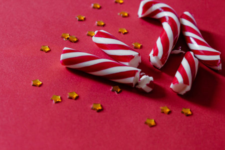 Stripped candy cane and confetti on red background