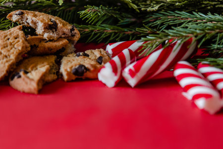 Christmas tree branch, stripped candy and cookies on red tableの写真素材