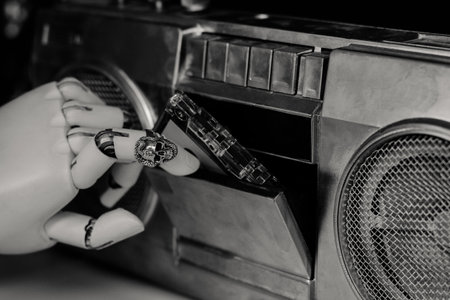 Robot hand with silver scull shape ring put cassette into the playerの写真素材