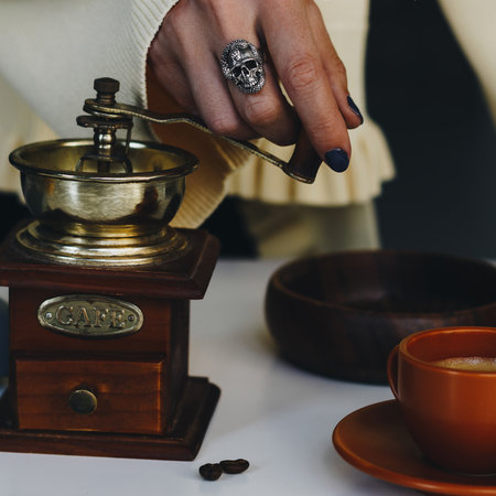 Close up of a woman hand with silver ring using vintage wooden coffee grinderの写真素材