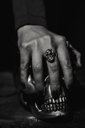Woman hand with silver scull shape ring holding human scullの写真素材