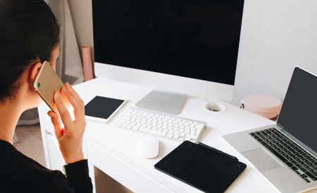 Back view of woman talking phone at home officeの写真素材