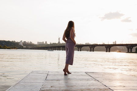 Back view of young woman with beautiful long hair standing on the pierの写真素材